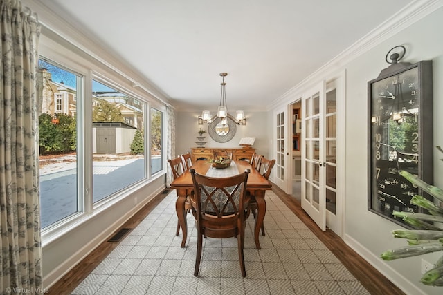 dining room featuring french doors, ornamental molding, wood-type flooring, and a notable chandelier