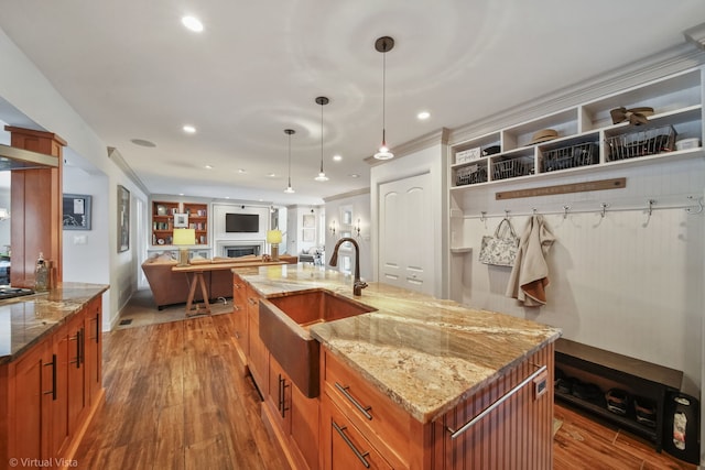 kitchen with pendant lighting, sink, a spacious island, wood-type flooring, and light stone countertops