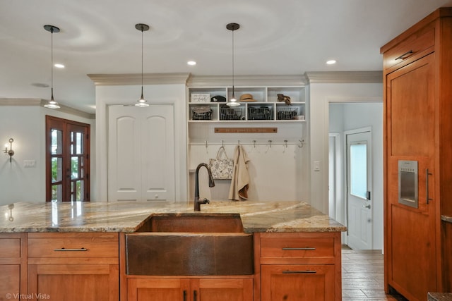 kitchen with crown molding, light stone countertops, sink, and hanging light fixtures