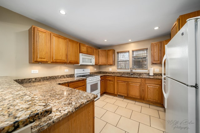 kitchen with light tile patterned floors, sink, dark stone countertops, and white appliances