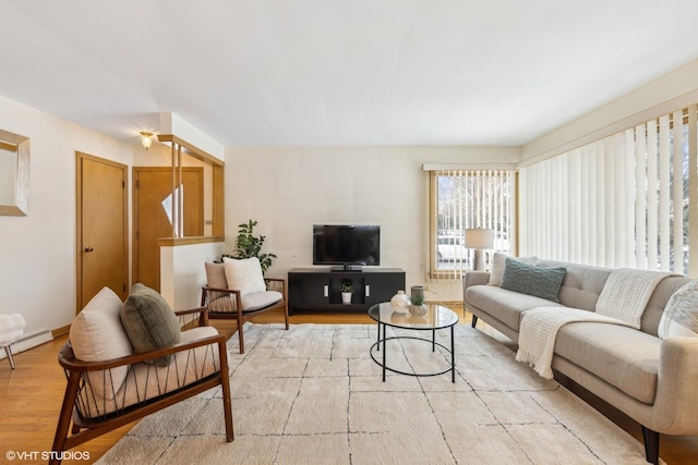 living room with a baseboard heating unit and light hardwood / wood-style flooring