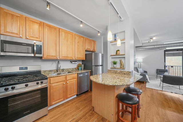 kitchen with light stone countertops, a center island, a breakfast bar, appliances with stainless steel finishes, and sink