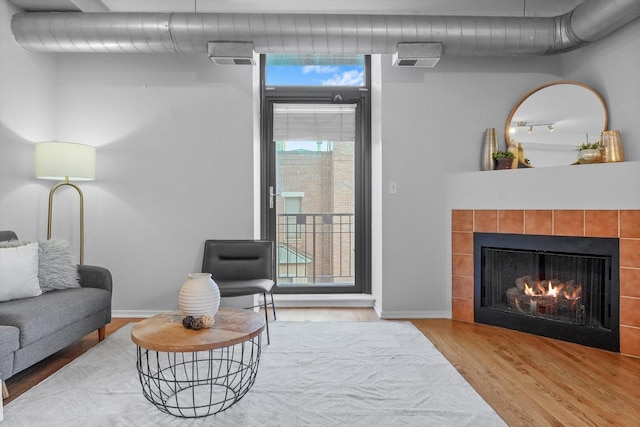 living room with a tile fireplace and hardwood / wood-style floors