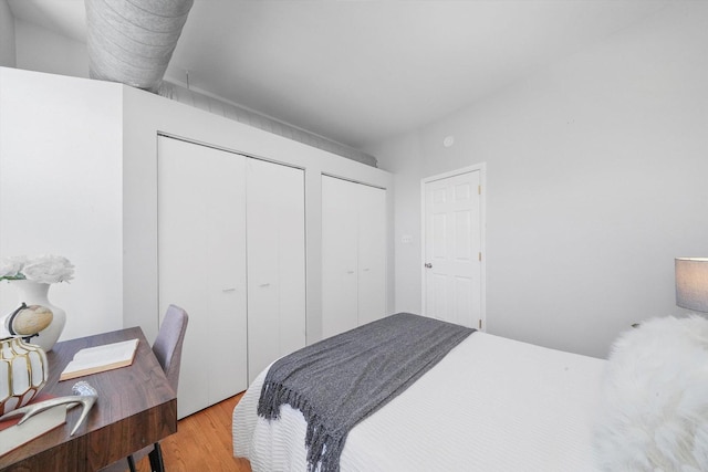 bedroom with multiple closets and light hardwood / wood-style flooring