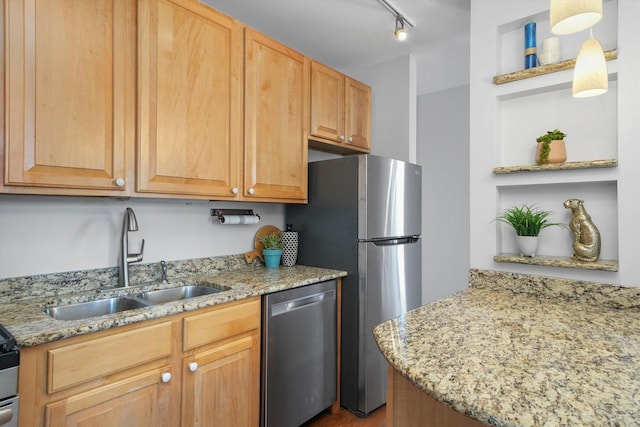 kitchen featuring light stone counters, hanging light fixtures, stainless steel appliances, track lighting, and sink