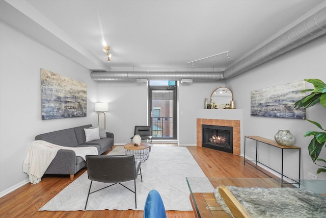 living room with light hardwood / wood-style floors, rail lighting, and a tile fireplace