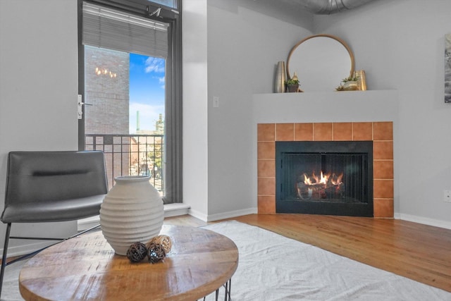 living area with hardwood / wood-style flooring and a tiled fireplace