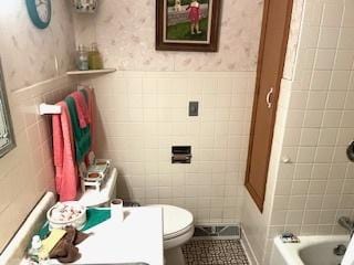 bathroom featuring tile patterned flooring, tile walls, and toilet