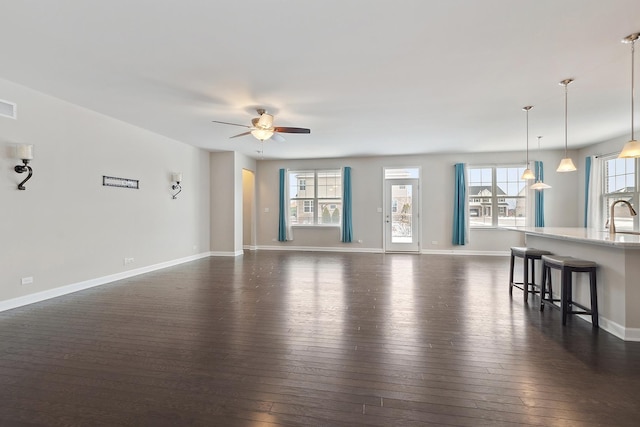 unfurnished living room with ceiling fan, sink, and dark hardwood / wood-style floors