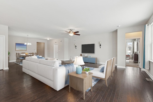 living room featuring ceiling fan with notable chandelier and dark hardwood / wood-style floors