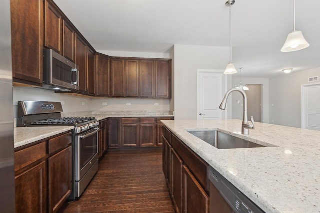 kitchen with light stone countertops, sink, pendant lighting, and stainless steel appliances