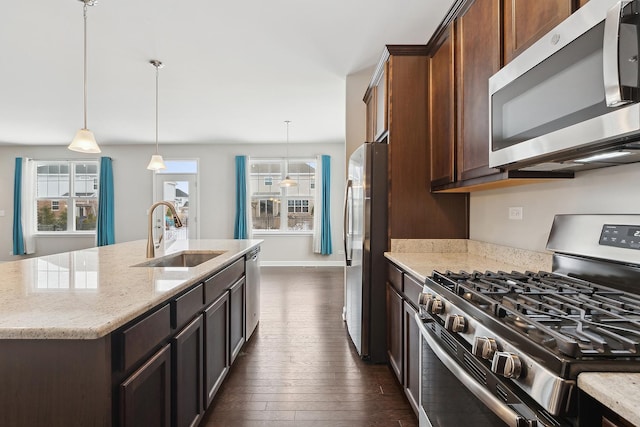 kitchen featuring decorative light fixtures, light stone countertops, sink, and stainless steel appliances