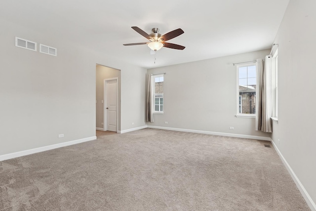 carpeted spare room with ceiling fan and plenty of natural light