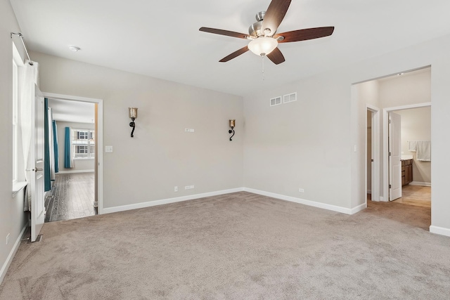 unfurnished bedroom with ceiling fan, light colored carpet, and ensuite bath