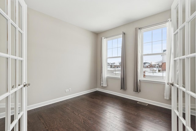 empty room with dark hardwood / wood-style flooring and french doors