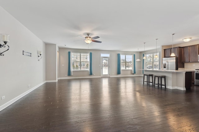 living room with ceiling fan, plenty of natural light, and dark hardwood / wood-style floors