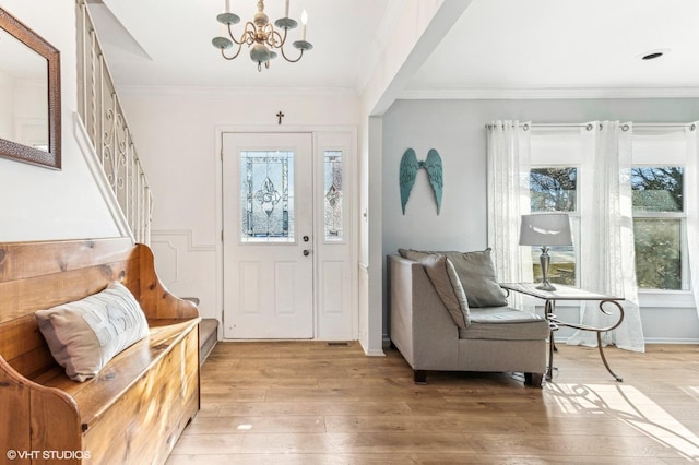 foyer entrance featuring light wood-type flooring, an inviting chandelier, and ornamental molding