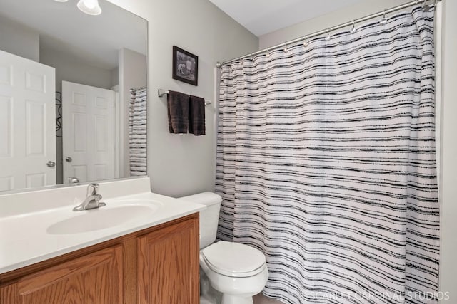 bathroom with curtained shower, toilet, and vanity