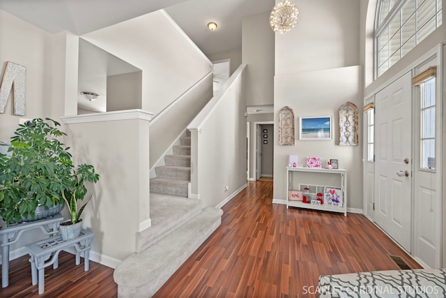 foyer entrance with plenty of natural light, dark hardwood / wood-style floors, a high ceiling, and an inviting chandelier