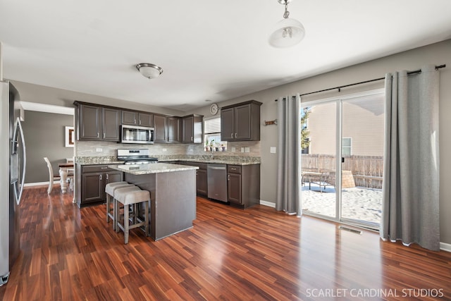 kitchen with a center island, dark hardwood / wood-style floors, dark brown cabinetry, and stainless steel appliances