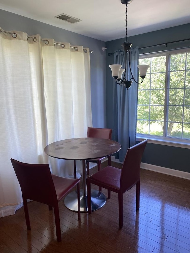 dining space featuring dark wood-type flooring, a wealth of natural light, and an inviting chandelier