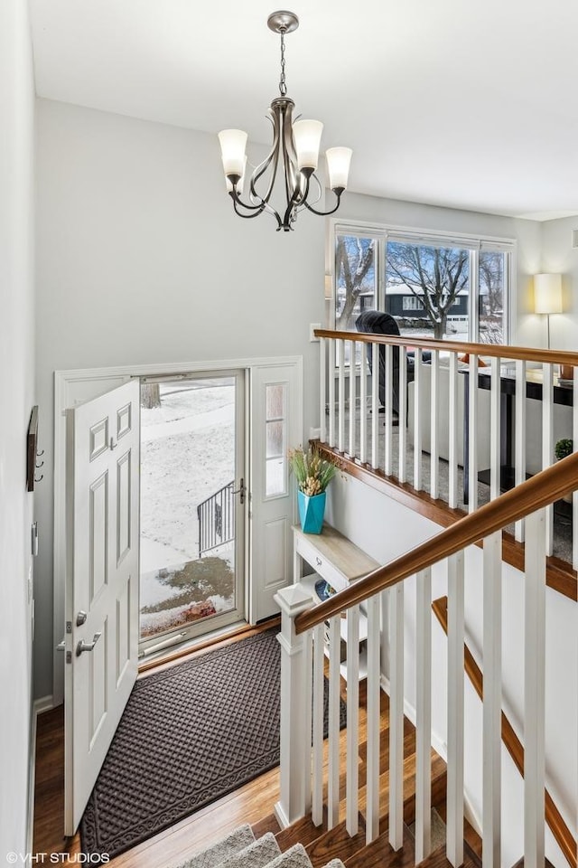 stairs with wood-type flooring and an inviting chandelier