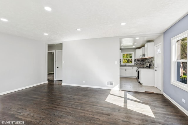 unfurnished living room with sink, a wealth of natural light, and dark hardwood / wood-style floors