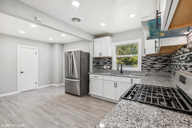 kitchen with light stone countertops, appliances with stainless steel finishes, white cabinetry, and sink