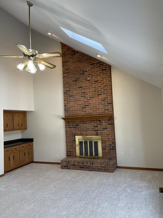 unfurnished living room with ceiling fan, light colored carpet, lofted ceiling with skylight, and a brick fireplace