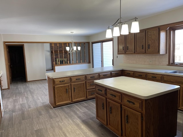 kitchen with an inviting chandelier, decorative light fixtures, a center island, dark hardwood / wood-style flooring, and kitchen peninsula