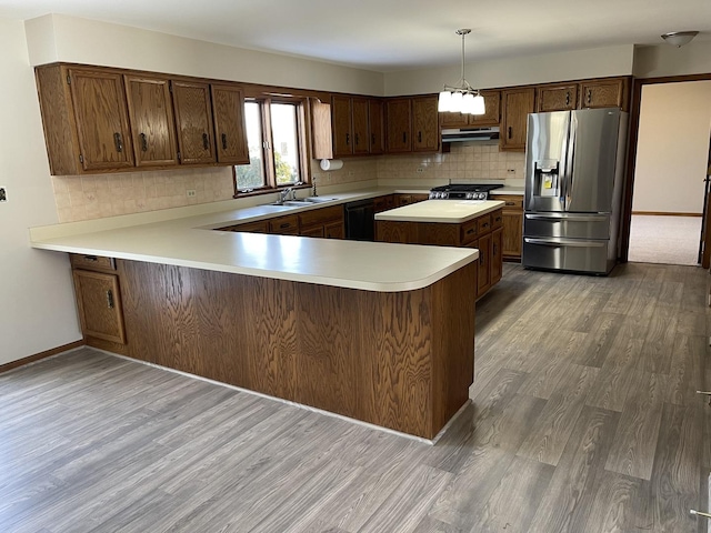 kitchen with stainless steel fridge, hanging light fixtures, hardwood / wood-style floors, black dishwasher, and kitchen peninsula