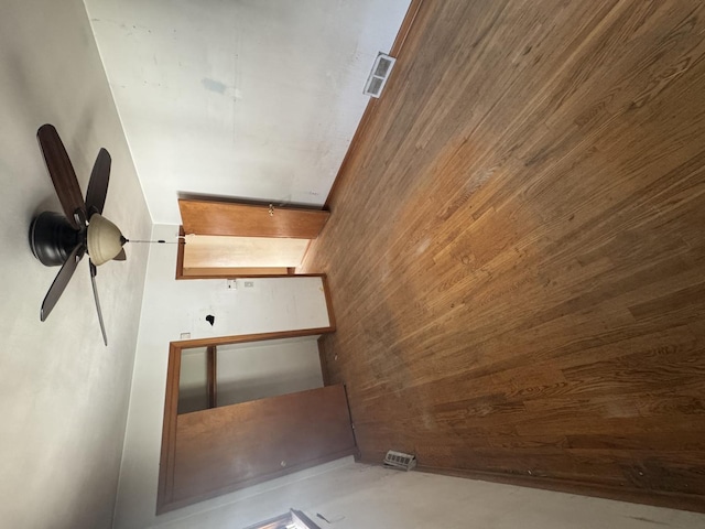 interior space featuring ceiling fan and wood walls