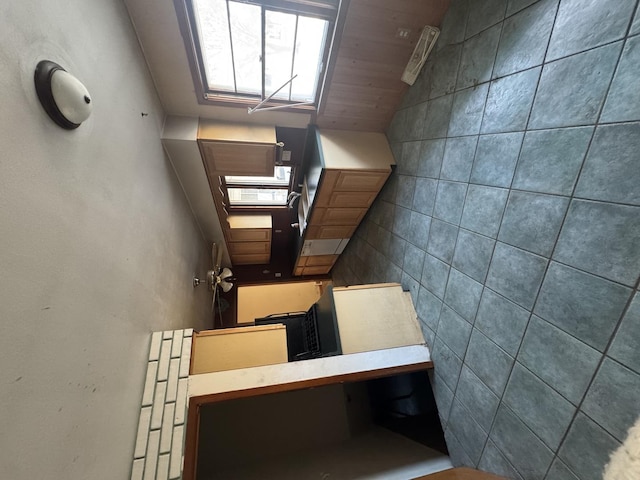 kitchen featuring lofted ceiling, wooden ceiling, and tile walls