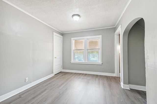 unfurnished room featuring a textured ceiling, light wood-type flooring, and crown molding