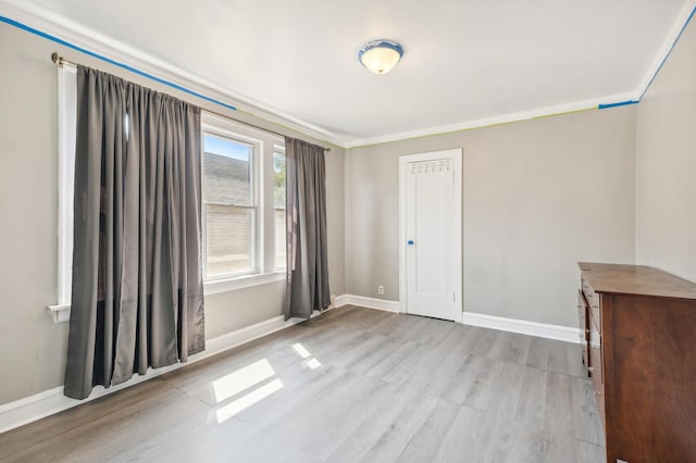 empty room featuring light wood-type flooring and crown molding