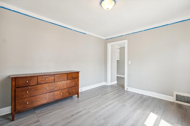 unfurnished bedroom featuring light hardwood / wood-style floors and crown molding