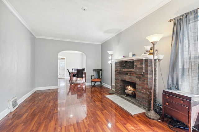 living room with a brick fireplace, crown molding, and dark hardwood / wood-style floors