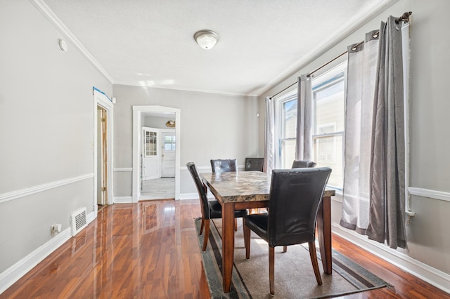 dining space with a textured ceiling, crown molding, and wood-type flooring