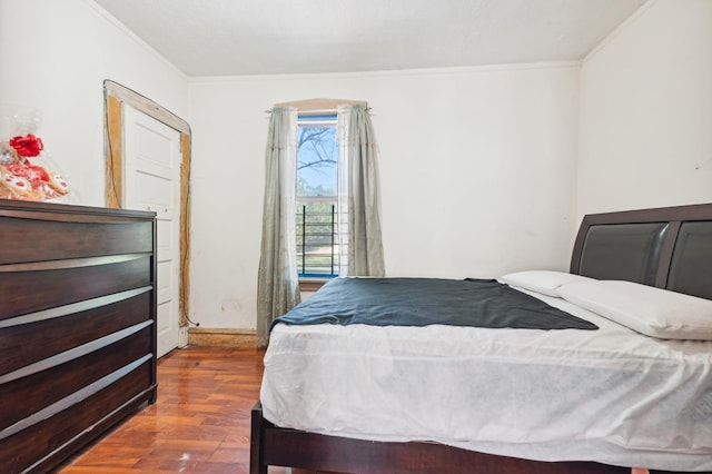 bedroom with ornamental molding and dark hardwood / wood-style floors