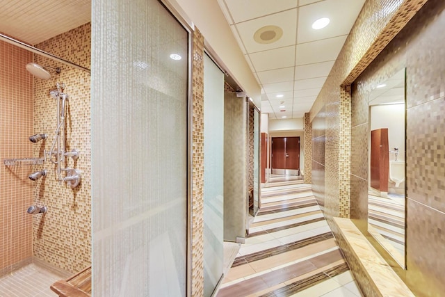 hall featuring a paneled ceiling and light tile patterned floors