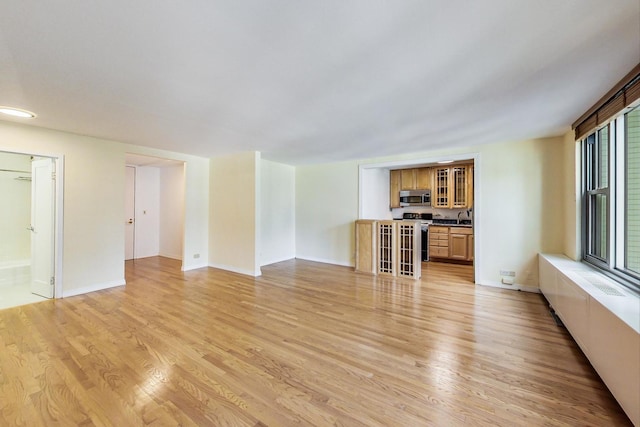 unfurnished living room featuring sink and light wood-type flooring