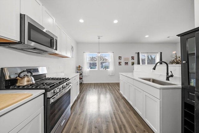 kitchen featuring stainless steel appliances, sink, decorative light fixtures, white cabinetry, and an inviting chandelier