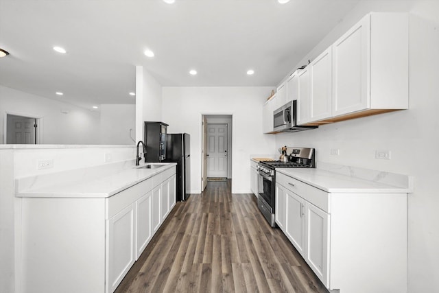 kitchen with appliances with stainless steel finishes, dark hardwood / wood-style flooring, white cabinetry, and sink