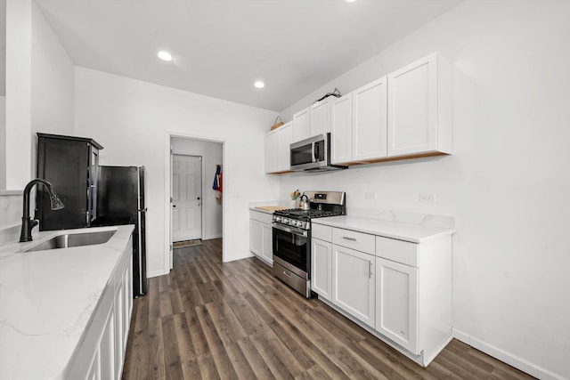 kitchen with white cabinets, appliances with stainless steel finishes, light stone countertops, and sink