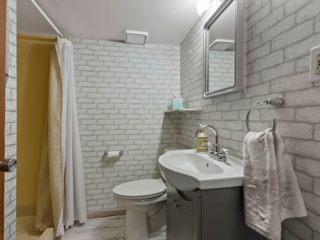 bathroom featuring a shower with curtain, brick wall, toilet, and vanity