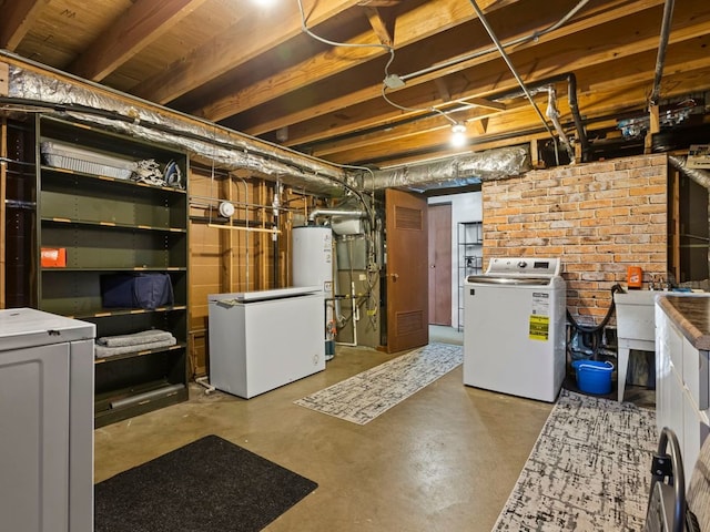 basement with brick wall, water heater, refrigerator, and washer and dryer