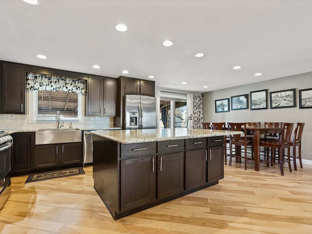 kitchen featuring stainless steel appliances, a center island, dark brown cabinets, and sink