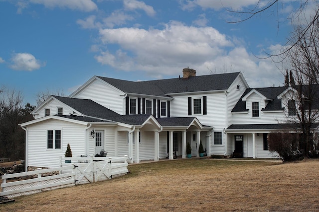 view of front of house with roof with shingles, a chimney, a front yard, and fence