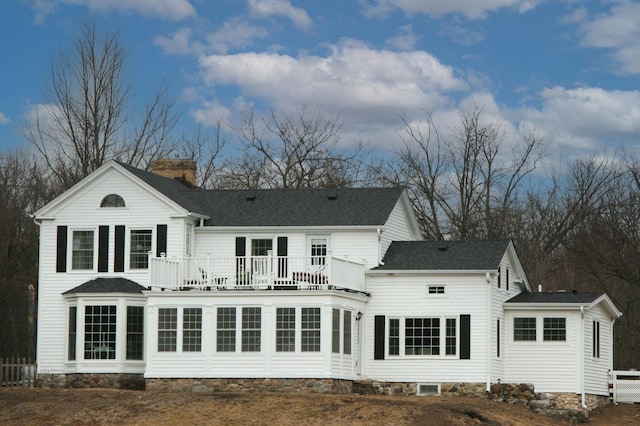 rear view of property with a shingled roof and a chimney