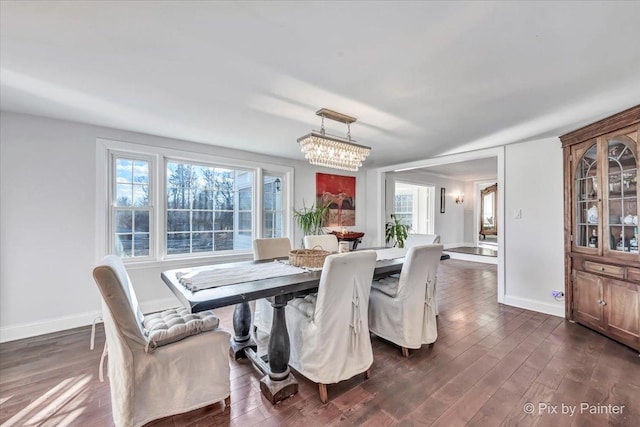 dining area featuring a chandelier, dark wood finished floors, and baseboards